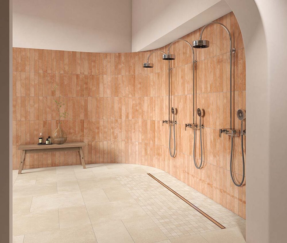 Cottofarbene Wandfliesen im länglichen Format mit matter und glänzender Struktur in einer offenen Dusche mit drei Brausen.