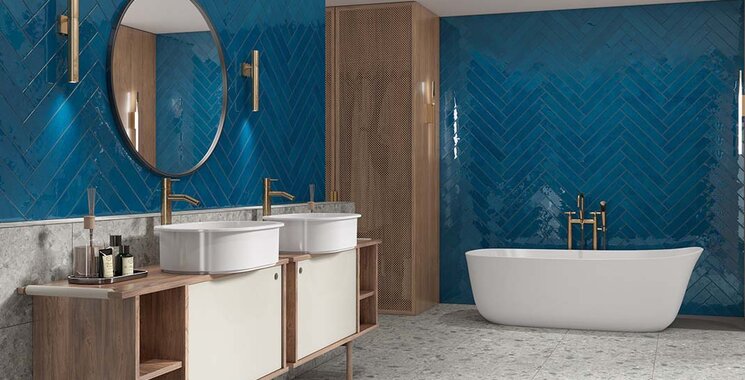 Kobaltblaue Wandfliesen im Fischgrätmuster mit glänzender Oberfläche in einem modernen Badezimmer mit freistehender Badewanne.