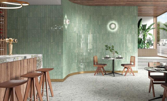 Längliche grüne Wandfliesen in Kombination mit Holz- und Steinelementen in moderner Café- oder Bar-Atmosphäre.
