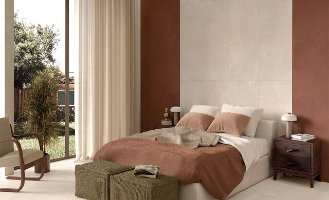 Natursteinoptik-Fliese im hellen Schlafzimmer mit warmen Farben und großen Fensterfronten