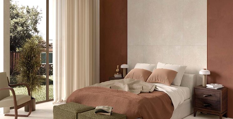Natursteinoptik-Fliese im hellen Schlafzimmer mit warmen Farben und großen Fensterfronten