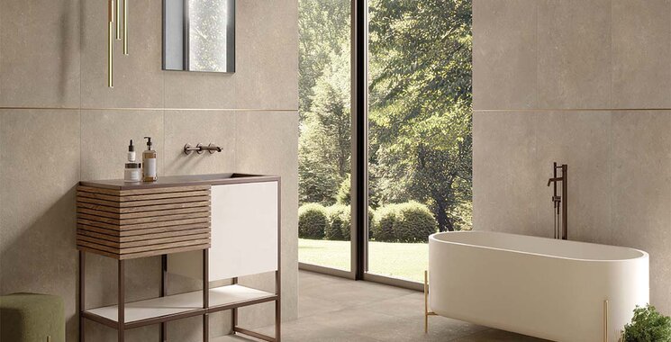 Zeitlose Natursteinoptik-Fliese im Bad mit freistehender Wanne und Blick ins Grüne