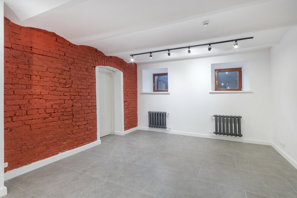 Kellerraum mit grauen Fliesen und roter Backsteinwand