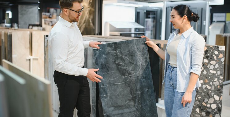 Beratungsgespräch in einer Fliesenausstellung mit großformatiger Fliese in dunkler Natursteinoptik
